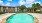 Large sparkling blue pool with a large pool deck and lounge chairs