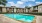 Large sparkling blue pool with a large pool deck and lounge chairs